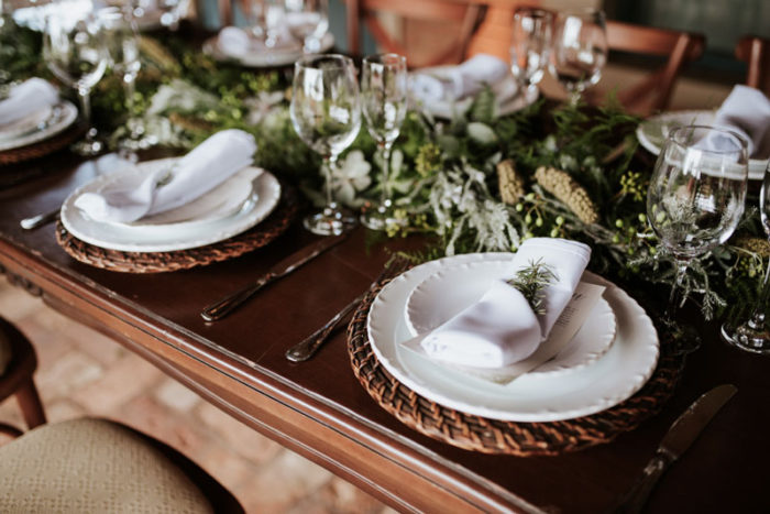 mesa posta com louças brancas e folhagens verdes