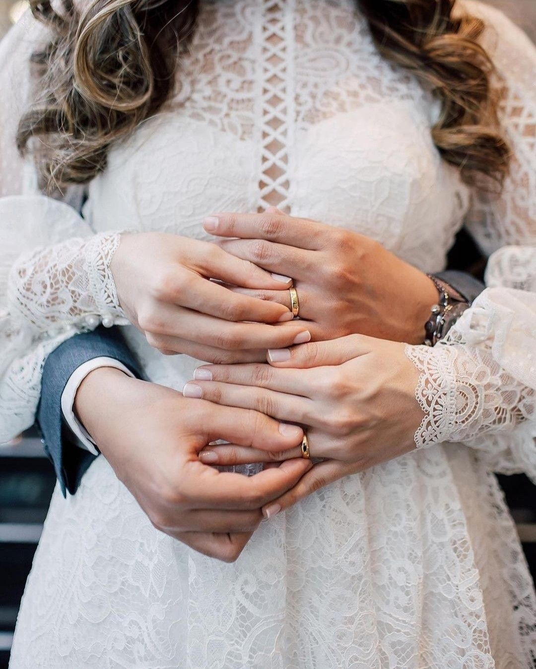 Ideia de foto com alianças de ouro bonitas em destaque nas mãos dos noivos.